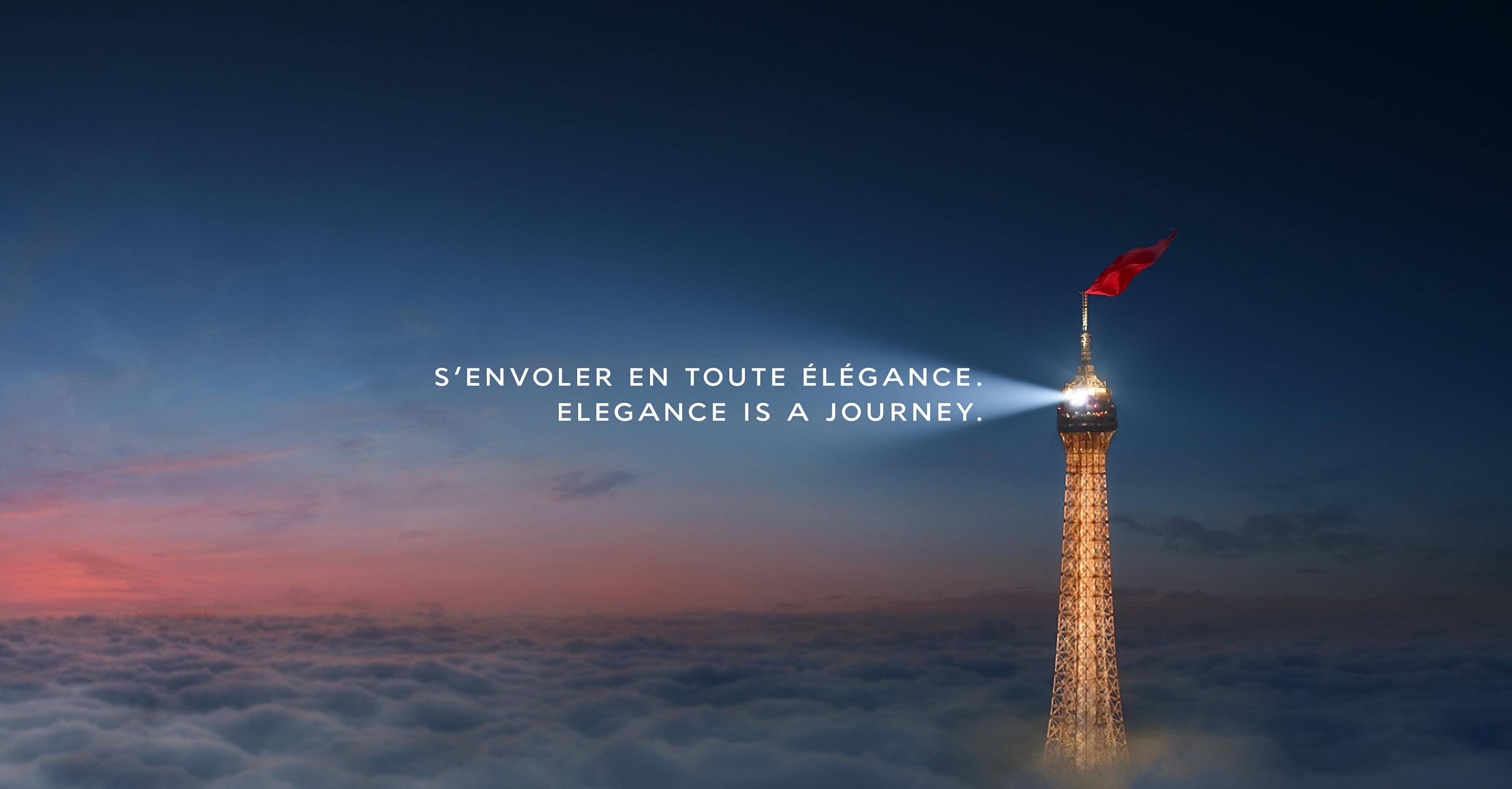 The eiffel tower shining light above the clouds